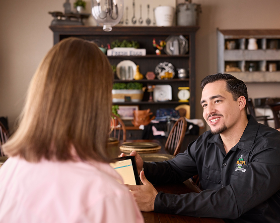 Wildlife removal professional speaking with a homeowner  using a tablet to explain services and build trust through clear communication.