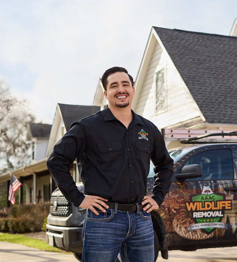 confident_professional Smiling wildlife removal professional standing confidently in front of a branded service truck and suburban home, ready to assist with expert care.