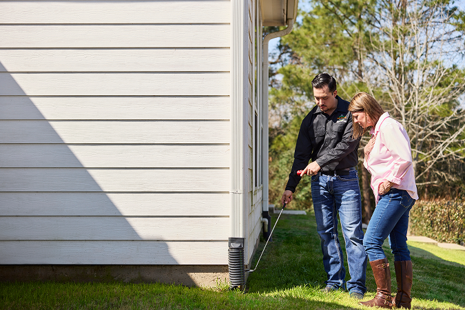 Wildlife control expert showing a homeowner evidence of animal entry points along the home’s exterior, highlighting a thorough inspection process.